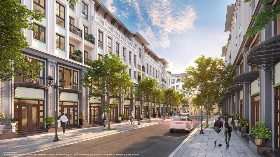 Dãy nhà liền kề cao 4-5 tầng phong cách tân cổ điển, mặt tiền đồng nhất với cửa kính lớn, ban công cây xanh, vỉa hè rộng rãi có người đi bộ, xe cộ di chuyển trên con phố nội khu thoáng đãng.