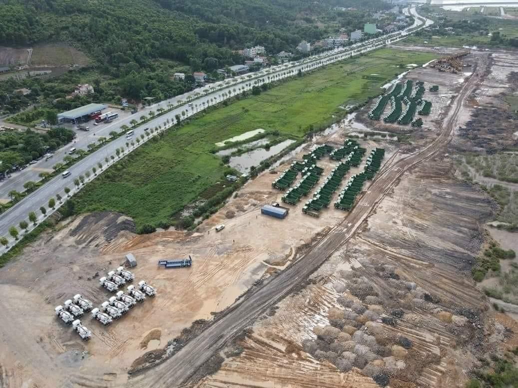 Liên hệ 1 Toàn cảnh công trường The Fullton với hàng loạt xe tải, máy xúc và thiết bị xây dựng trên khu đất rộng lớn, gần đường cao tốc và vùng đất ngập nước, với khung cảnh thiên nhiên xung quanh.